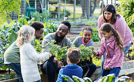 Man teaching children about plants in community garden