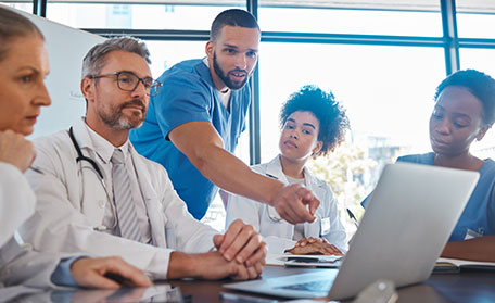 Medical professional shows team something on a laptop
