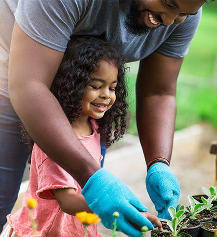 Father teaching daughter to take care of garden