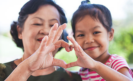 grandmother and grandchild make a heart with hands