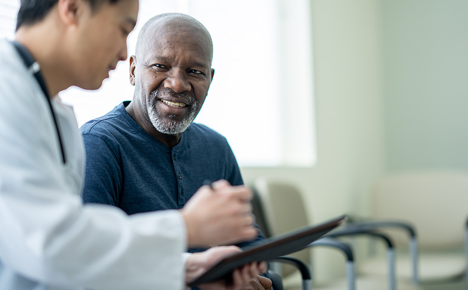 Senior man talking with doctor looking at tablet